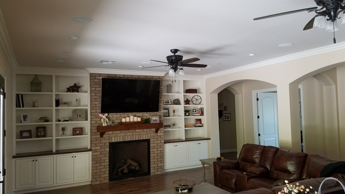 TV mounted above a brick fireplace with built-in bookshelves in a two-story family room